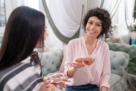 Having tea. Two dark-haired women having good time while having teaの写真素材