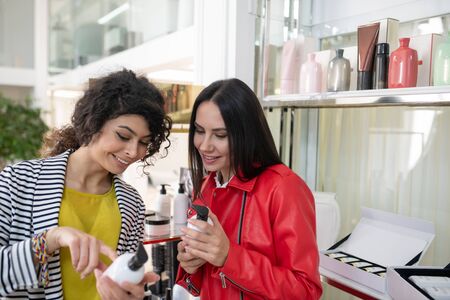 Hair care products. Two beaming ladies choosing hair care productsの写真素材
