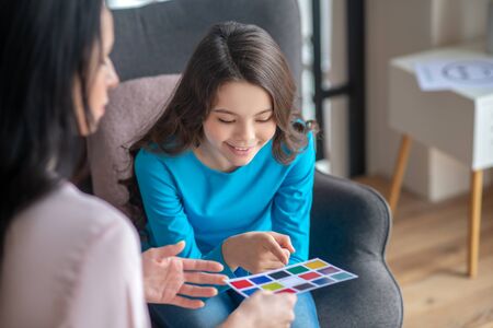 Smiling. Long-haired teen in a blue shirt looking at the color palette and smilingの写真素材
