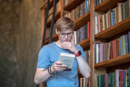 Involved. Young man in eyewear reading a book and loooking involvedの写真素材