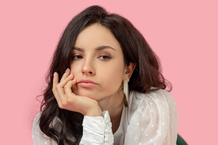 Feeling blue. Young pretty brunette woman in a white blouse looking moodyの写真素材