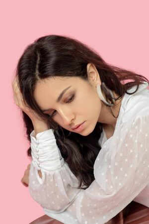 Upset. Young pretty brunette woman in a white blouse looking upset