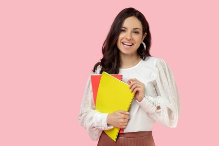 Feeling good. Young woman in a white blouse holding notebooks and looking contented