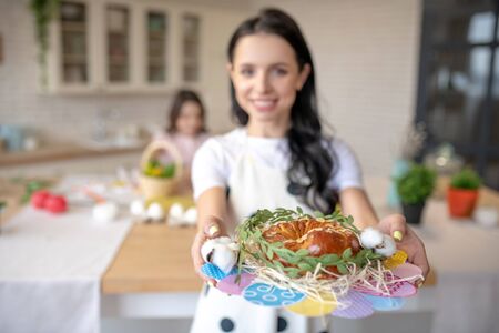 Easter buns. Cute smiling woman holding in hands a tray with easter buns