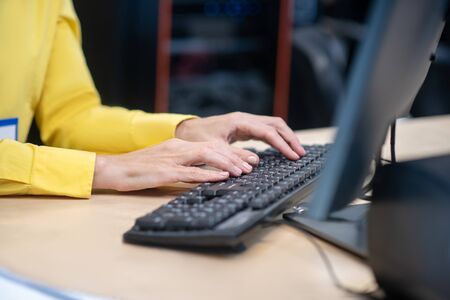 At work. Female hands typing on black keyboard, lying on desk