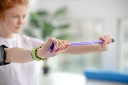At rehabilitation center. Female patient stretching jump rope with hands