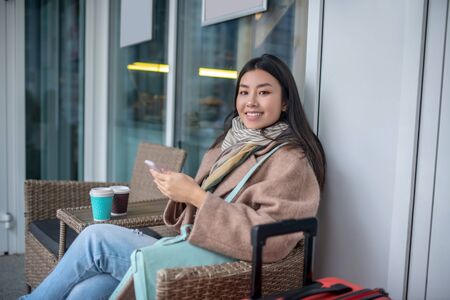 In the street cafe. Pretty asian young woman feeling good and positiveの写真素材