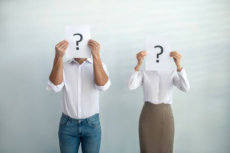 Uncertainty. Man and woman standing next close to each other holding question signs