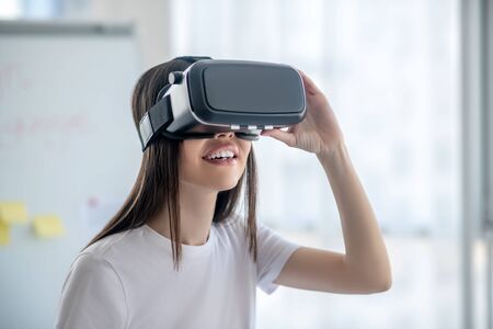 New technology. Dark-haired girl standing wearing vr headset and looking involved