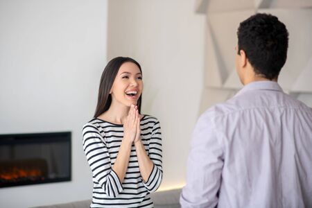Man standing with opposite a joyful smiling woman with dark hair, both are in the room.の写真素材
