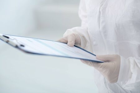 Protective measures. Close-up of medical worker hands in gloves holding clip folder