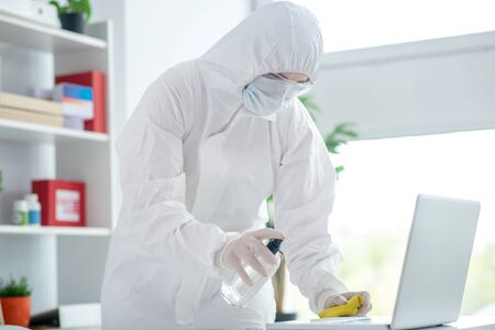 Disinfection. Person in protective workwear doing surface disinfection