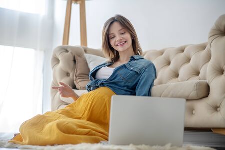 Connected. Young pregnant woman in a jeans jacket having a video callの写真素材