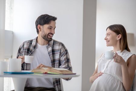 Morning tea. Dark-haired man and his pregnant wife having tea together