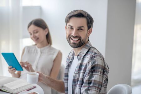 Pleasant morning. Cute young woman in a white dress and her husband spending morning togetherの写真素材