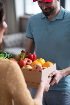 Delivery service. Dark-haired female customer receiving groceries from the male courrierの写真素材
