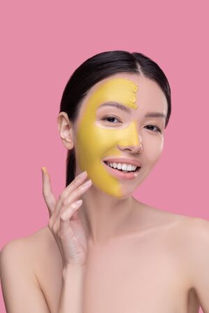 Yellow clay mask. Dark-haired pretty asian girl having face beauty proceduresの写真素材