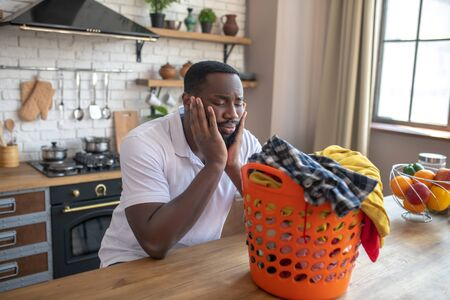 Feeling uncertain. African american man looking at the basket with clothes and looking shockedの写真素材
