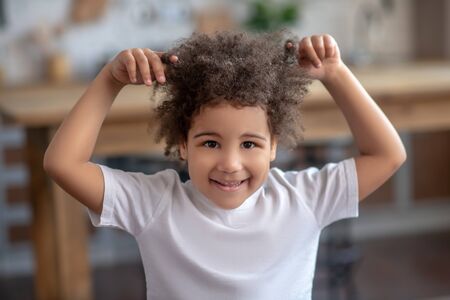 Naughty boy. Cute curly-haired kid in a white tshirt looking naughtyの写真素材
