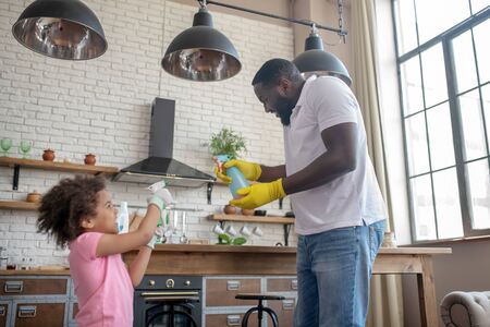 Spraying water. African american bearded man sparying water on his daugher while playingの写真素材