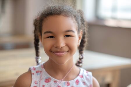 Happy girl. Cute curly-haired girl smiling and looking happyの写真素材