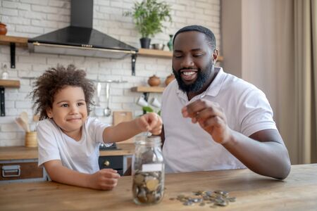 Saving money. Dark-skinned bearded man holding a coin into his handの写真素材