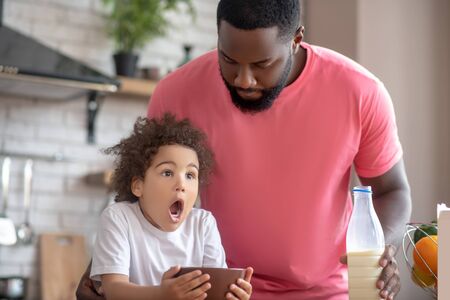 With open mouth. Cute little girl holding her plate and looking surprised with her mouth openの写真素材