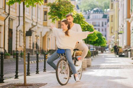 Fun moment. Cheerful young man and woman sitting in front with grimaces riding one bike on the sunny...