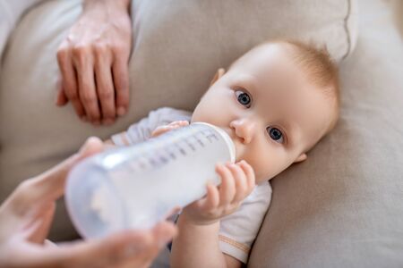 Feeding the baby. Fathers hands holding the bottle with milk for the baby