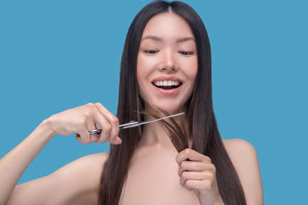 Hair treatment. A woman cutting split-ends of hl long dark hairの写真素材