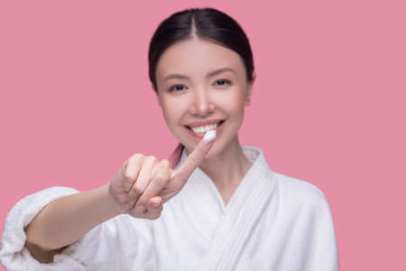Beauty formula. A smiling young woman applying novel facial creamの写真素材