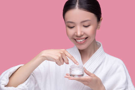 Dermatological product. A smiling young woman trying new cosmeological creamの写真素材