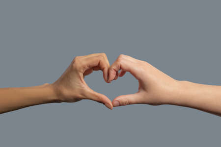 Brotherhood of mankind. Close-up of light-skinned and dark-skinned hands shaping in heartの写真素材