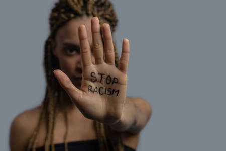 Stop racism. Young African American woman showing palm with stop racism letteringの写真素材