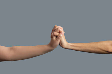Brotherhood. Close-up of fair-skinned and dark-skinned hands clenched togetherの写真素材