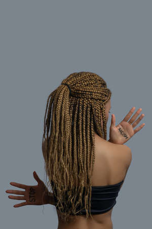 Stop racism. Young African American woman in black top standing back to camera, showing palms with...