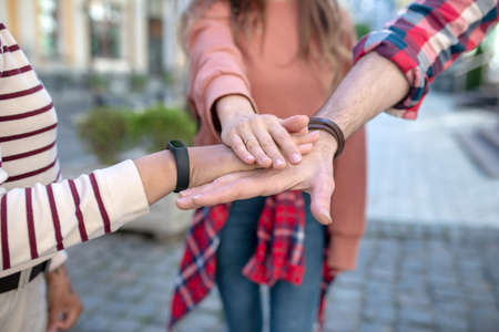 Best friends. Male hand and two female gestures showing fidelity to friendship of three young people standing on city street, no faces are visibleの写真素材
