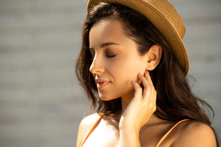 Beauty. Beautiful brunette girl in a straw hat closed her eyesの写真素材