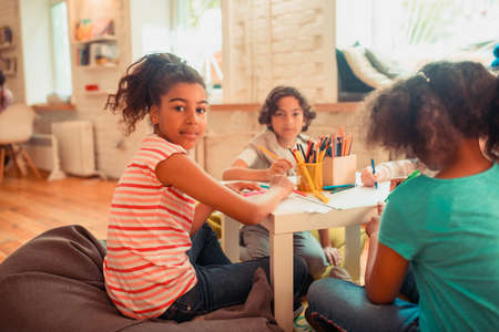 Art club. An African-American girl drawing together with her peersの写真素材