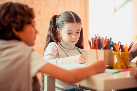 Learning art. A concentrated girl drawing with color pencils during the art classの写真素材