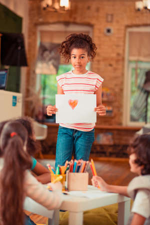Cute pictue. A girl showing a picture of the heart she drewの写真素材