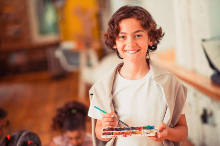 Talented kid. A smiling boy holding a palette of watercolorsの写真素材