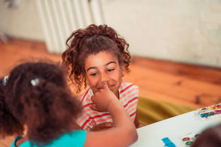 Having fun at school. A girl having her nose stained with watercolorsの写真素材