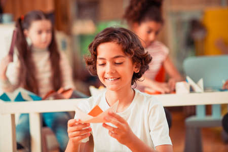 Paper boat. A smiling boy making a ship from paperの写真素材