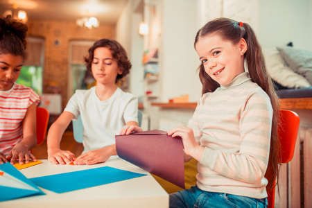 Tatanted kid. A girl creating origami from the sheet of paper