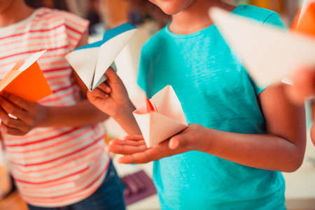 Paper crafts. A girl holding a paper boat and a paper planeの写真素材