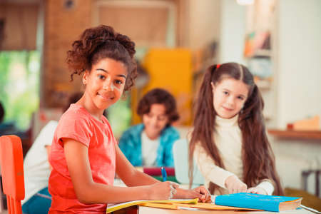 Peer support. A smiling girl doing her homework together with her classmate