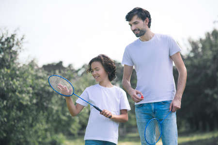 Badminton. Dark-haired boy holding badminton racket ready to play with his dadの写真素材