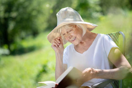 Reading stories. An attentive senior woman reading a book in a deck chairの写真素材