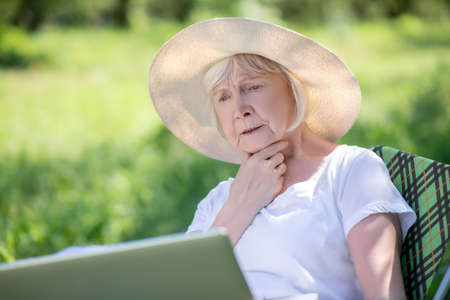 Leisure. A concentrated elderly woman working with the computer outdoor
